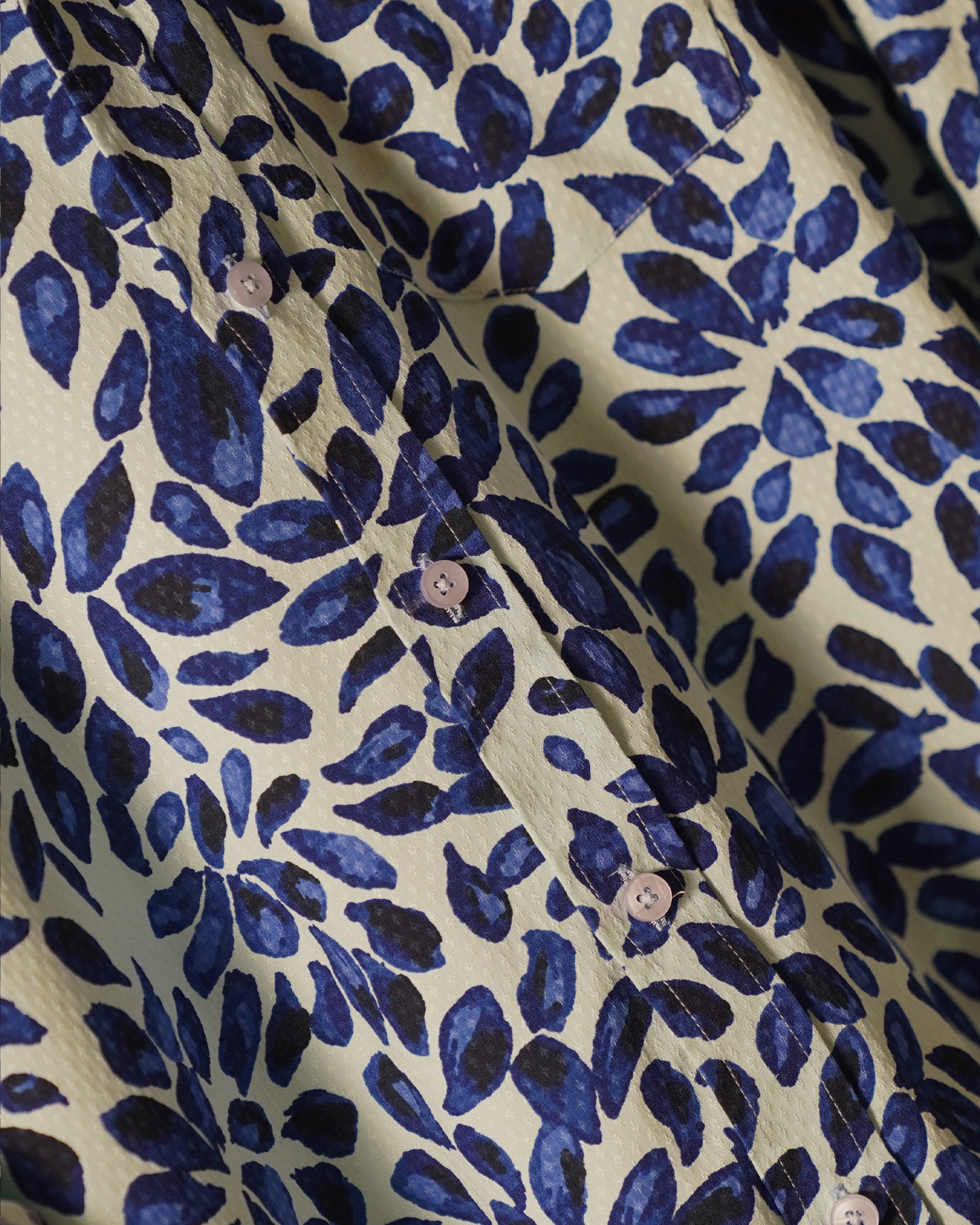 white cotton shirt featuring a bold abstract leaf print in deep blue tones