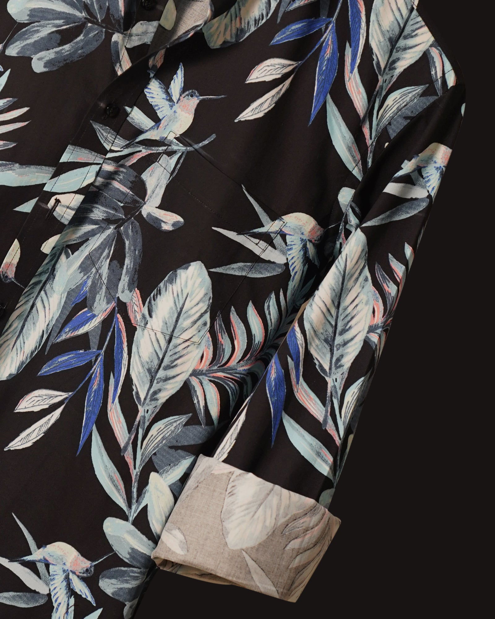 Black cotton shirt adorned with a striking tropical leaf print in shades of blue, grey, and subtle coral accents